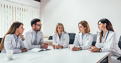 © bnenin / stock.adobe.com Gruppe von Ärztinnen und Ärzten diskutiert am Tisch