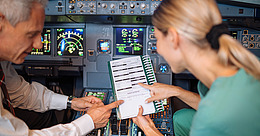Pilot und Ärztin schauen sich im Cockpit eines Flugzeugs Dokumente an