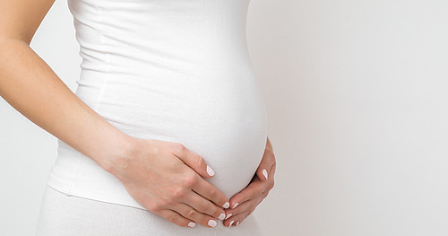 Schangere Frau umschließt ihren Babybauch