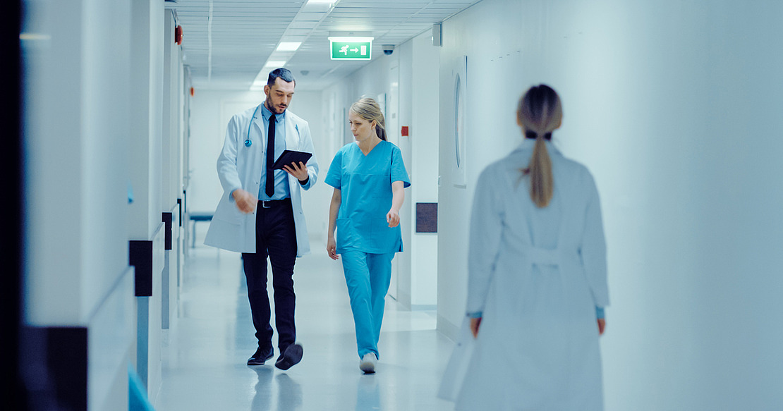 Junge Chirurgin und Arzt mit Tablet im Krankenhausflur