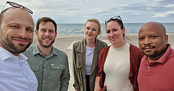 Die beiden Fellows posieren mit den Gastgolleginnen und Gastkollegen am Ostseestrand