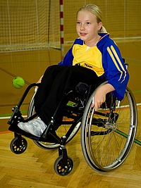 Mädchen im Rollstuhl vor Handballtor